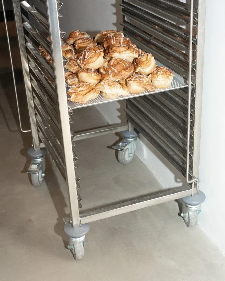Cuisine de boulangerie professionnelle avec hotte inox, cloison inox, cuisinier au travail et sol résine beige continu