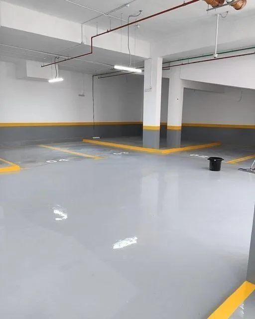 Zone d'emplacements PMR rénovée en résine blanche avec marquage et bordure, parking copropriété