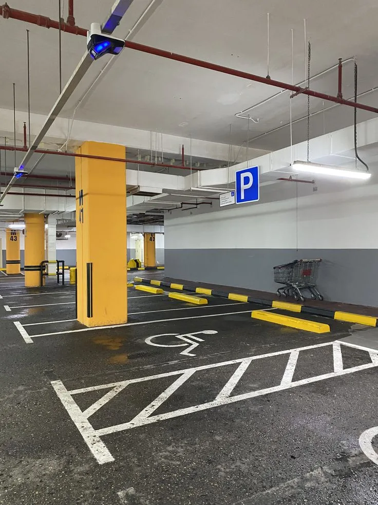 Parking béton avant rénovation, surface dégradée avec marquages anciens et bollards
