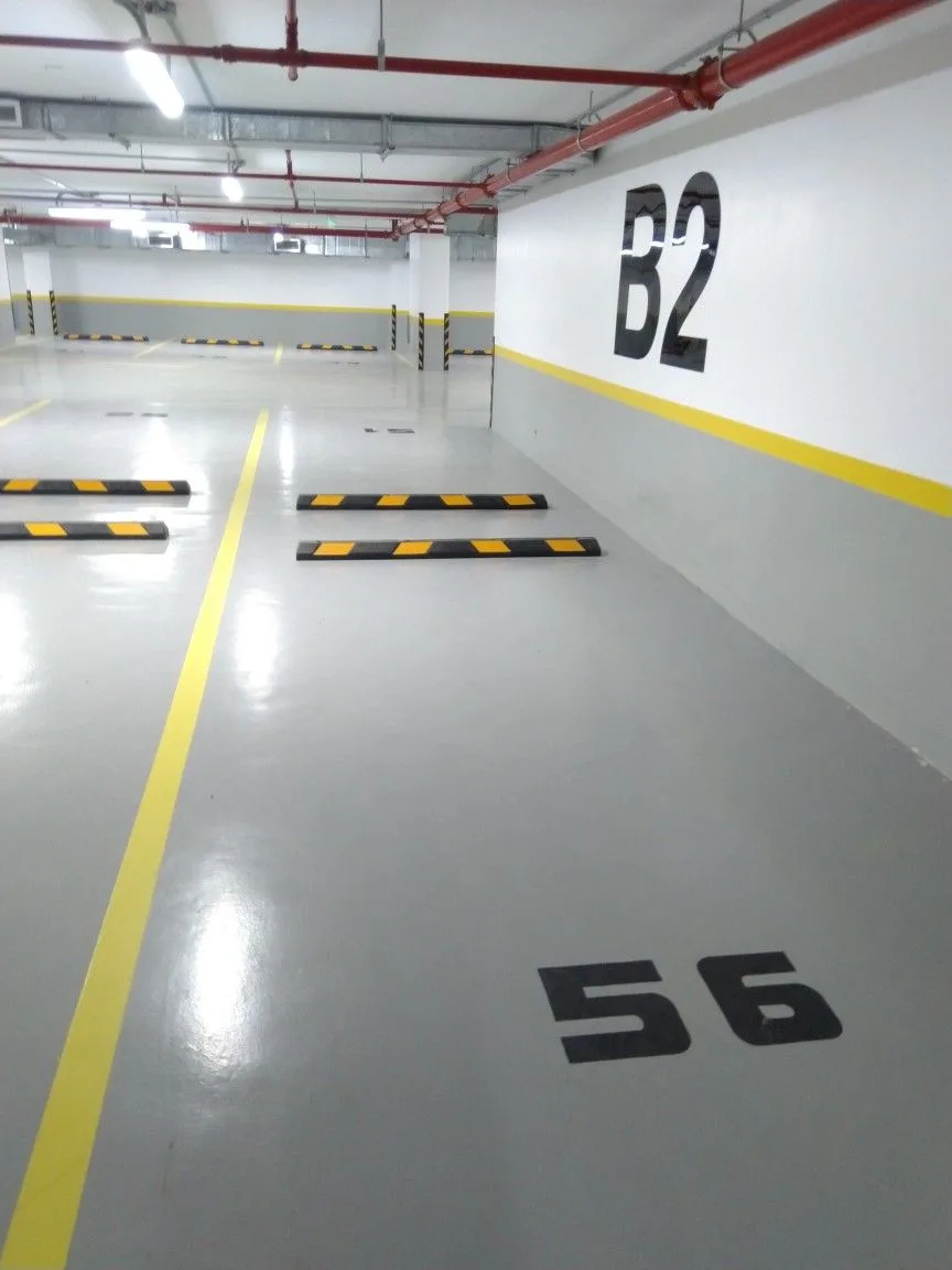 Vue d'ensemble parking résine avec repère de niveau B2 au mur et numéros d'emplacement au sol